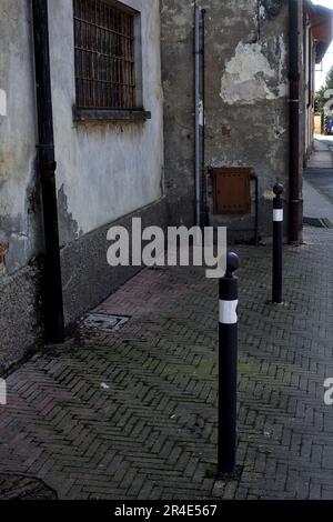 Pavement  on a street bordered by a worn out facade with windows and wooden doors in a village in the italian countryside Stock Photo