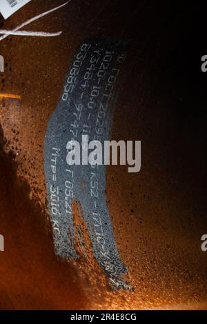 Marking of steel pipe. Close-up photo of numbers and letters on rusted metal Stock Photo