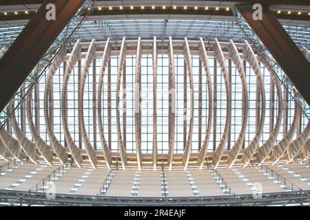 Image from below of a modern architecture building with a complex shape and pedestrian walkways. Reflective windows and the light blue sky in the back Stock Photo