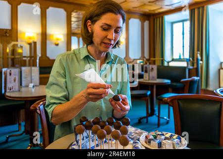 Production of Mozartkugeln still involves a lot of manual work at the Fürst confectionery. With a Stanitzel (piping bag) Doris Fürst closes the hole with a dab of chocolate. Salzburg, Austria Stock Photo