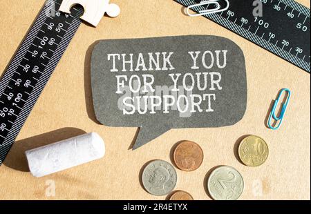 handwriting text thank you for your support is written in chalkboard on green light background and rustic wooden board, close up Stock Photo