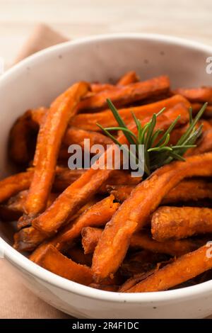 Sweet tasty potato fries and rosemary in bowl, closeup Stock Photo