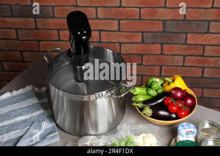 Sous vide cooker in pot and ingredients on table. Thermal immersion circulator Stock Photo