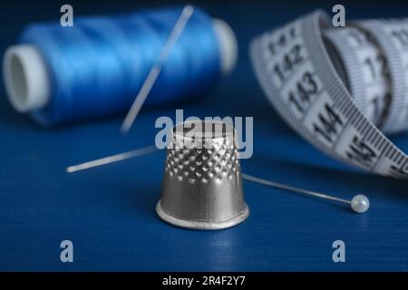Silver thimble on blue wooden table. Sewing accessories Stock Photo