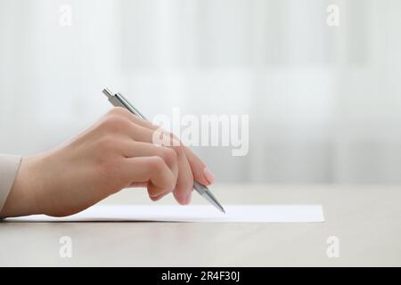 Woman writing on sheet of paper at table, closeup Stock Photo