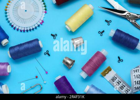 Flat lay composition with thimbles and different sewing tools on light blue background Stock Photo