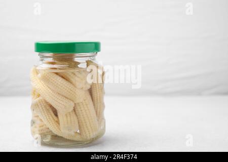 Canned baby corns on white table, closeup. Space for text Stock Photo