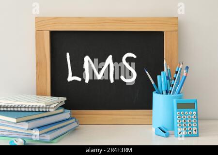Learning management system. Small chalkboard with abbreviation LMS on light table with stationery Stock Photo