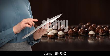 Production line of chocolate candies. Woman working with tablet, closeup. Banner design Stock Photo