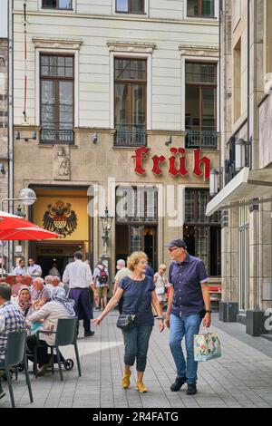 Senior couple enjoying a day of shopping as they pass by the famous Cologne beer hall called the Fruh.  World famous landmark drinking establishment. Stock Photo