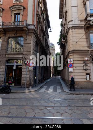 Pedestrian beside a pedestrian crossing over a narrow street with elegant properties with balconies in the Brera district of Milan, Lombardy, Italy Stock Photo