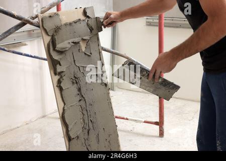 Worker spreading adhesive mix over tile with spatula, closeup Stock Photo