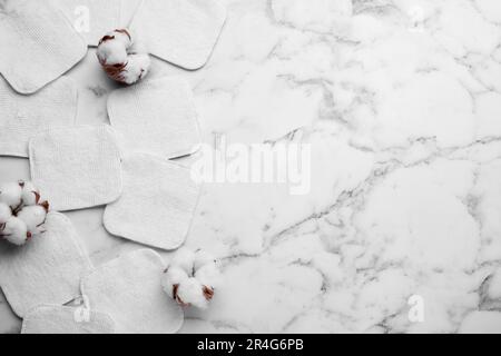 Flat lay composition with many clean cotton pads and flowers on white marble table. Space for text Stock Photo