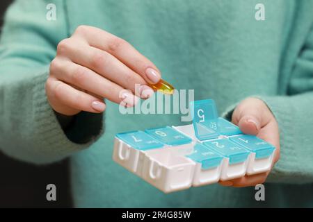 Woman taking pill from plastic box , closeup Stock Photo