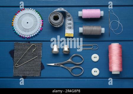Flat lay composition with thimbles and different sewing tools on blue wooden table Stock Photo