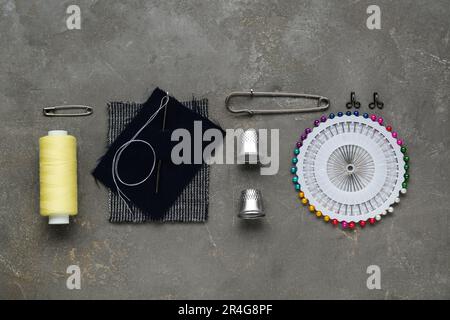 Flat lay composition with thimbles and different sewing tools on grey table Stock Photo