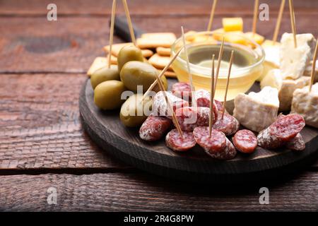 Toothpick appetizers. Pieces of sausage, cheese and honey on wooden table, space for text Stock Photo