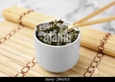 Chopped nori sheets with chopsticks on white marble table, closeup Stock Photo