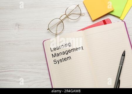 Notebook with text Learning Management System on white wooden table, flat lay. Space for text Stock Photo
