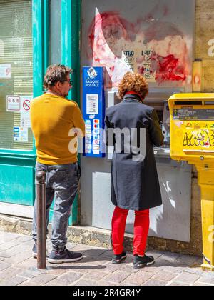 Couple at cash dispenser in city - Tours, Indre-et-Loire (37), France. Stock Photo