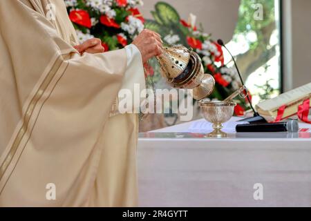Sunday mass in a catholic church. The priest uses the thurible at the beginning of the celebration to also incense the Gospel and give solemnity Stock Photo