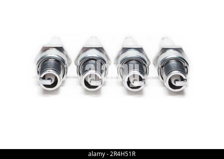 Four spark plugs on a white background, close-up Stock Photo