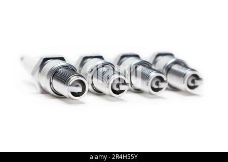 Four spark plugs on a white background, close-up Stock Photo