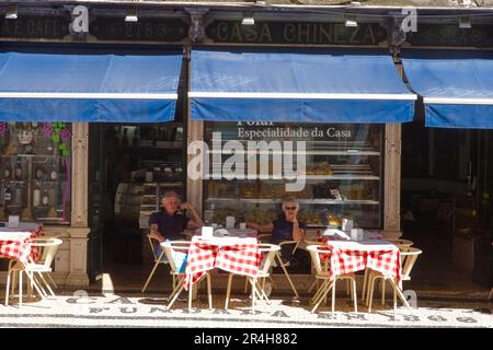 Couple seated in the shade outside the casa chineza cafe in the centre of Lisbon Stock Photo
