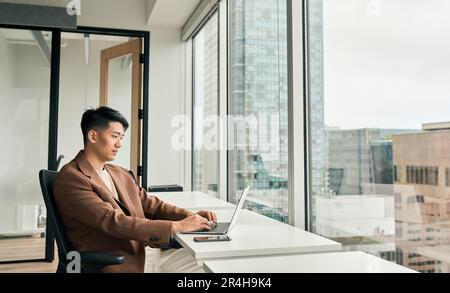 Young Asian business man manager working on laptop in corporate office. Stock Photo