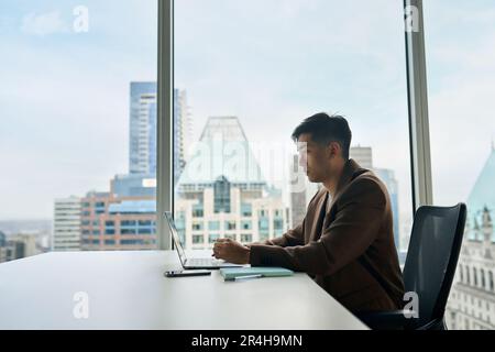 Young Asian business man working on laptop computer in office. Stock Photo