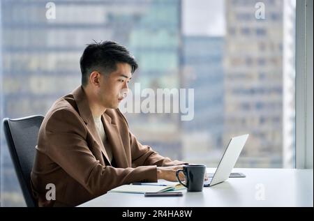 Busy professional Asian business man working typing on laptop in office. Stock Photo