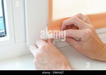 Close-up of male hands installing roller blinds on the window. Installation of roller blinds Stock Photo