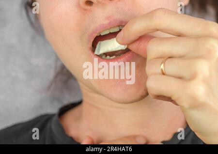 A woman puts a packet of Swedish snus into her mouth. Swedish snus Stock  Photo