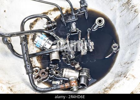 Close-up, a fuel pump has all connector elements separated from the tractor engine and kept in a bowl. Stock Photo