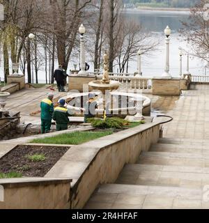 Communal professional workers carry out spring cleaning of fountains and waterfalls from garbage, silt and moss in a public park. Using special tools Stock Photo