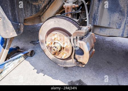 Worn used car brake disk close up. Repairing brakes on a car. Changing wheels and brakes. Rusty disc brakes of a car Stock Photo