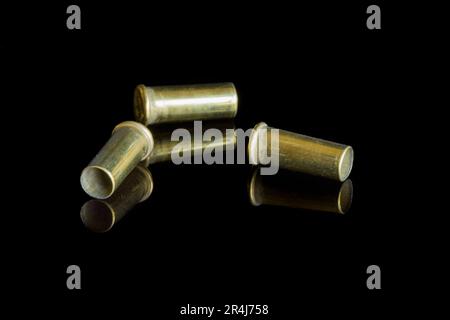 Three empty cartridges of small caliber ammunition bullets. With reflection on a black background. Stock Photo
