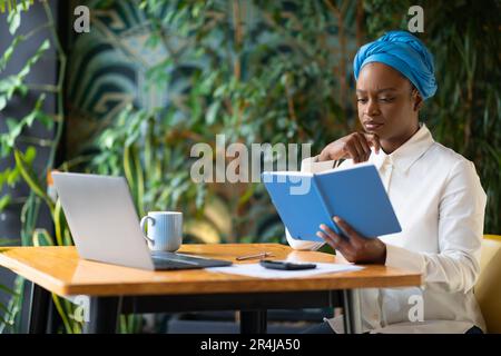 Business analyst working remotely at cafe, using laptop, calculator Stock Photo