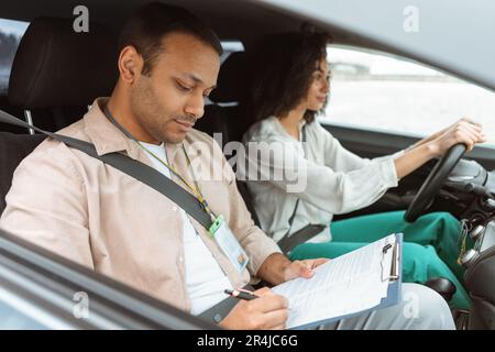 Arabic Instructor Taking Notes Teaching Novice Driver Woman Driving Car Stock Photo