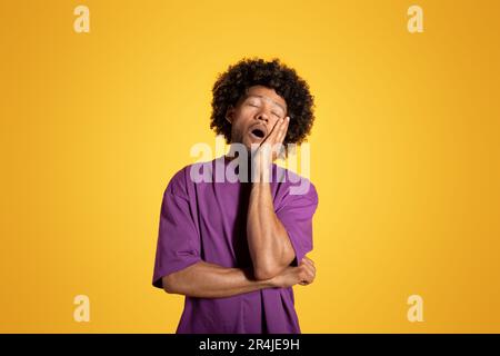 Tired exhausted funny bored mature black curly man in purple t-shirt sleeping with open mouth Stock Photo