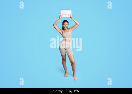 Happy young european slim woman athlete brunette in sportswear shows calendar Stock Photo
