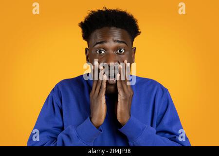 Shocked black man looking at camera, yellow background Stock Photo
