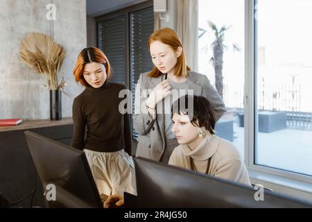 Multiracial female programmers discussing over computer at desk in startup office Stock Photo