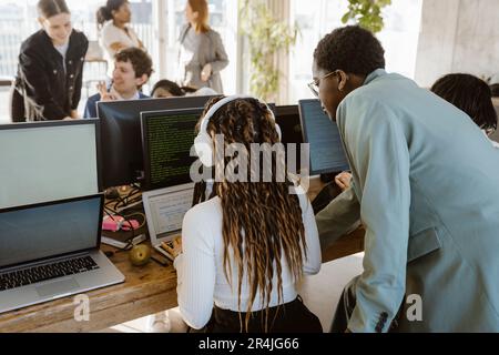 Multiracial programmers discussing over laptop at desk in office Stock Photo