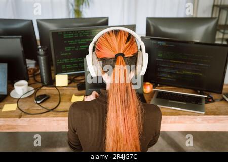 Rear view of female programmer working on laptop in creative office Stock Photo