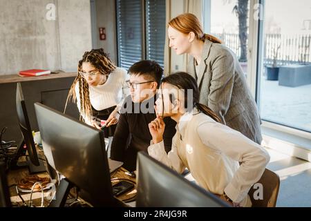 Multiracial male and female programmers discussing over computer in creative office Stock Photo
