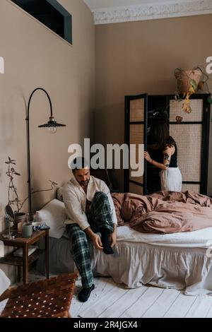 Man wearing sock while sitting on bed at home Stock Photo