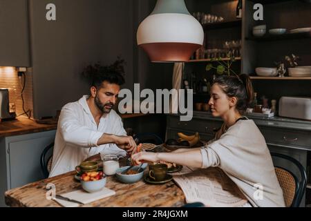 Couple having breakfast with each other at dining table in home Stock Photo