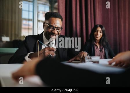 Happy mature businessman examining documents sitting in board room at office Stock Photo