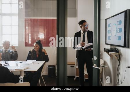Male and female business colleagues discussing over presentation in board room at office Stock Photo